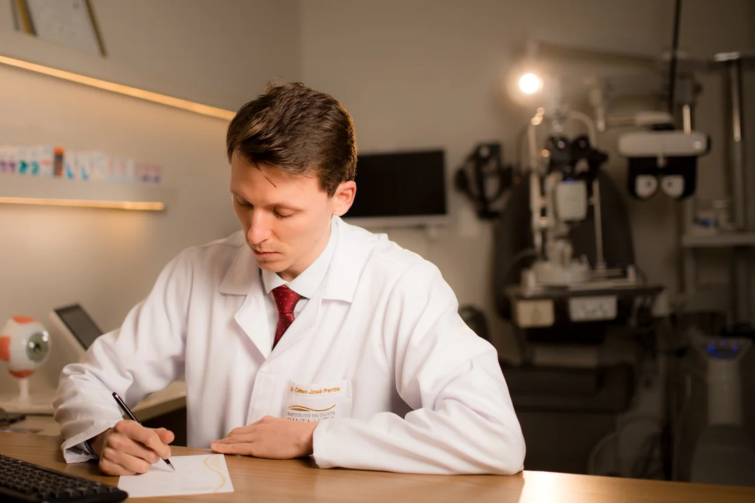 Dr. Celso Pertile escrevendo uma orientação durante a consulta